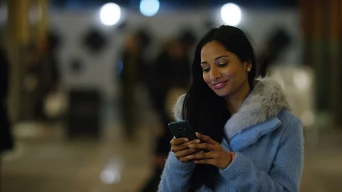 Young Indian female using her phone outdoors in the high street Vidéo 100342886