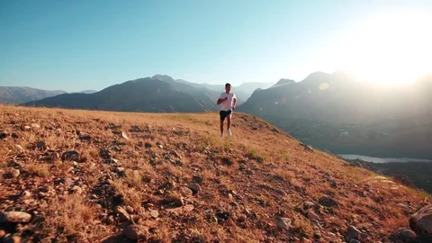 Young Indian guy doing a morning jog through mountainous terrain, slow motion Stock Footage 69972602