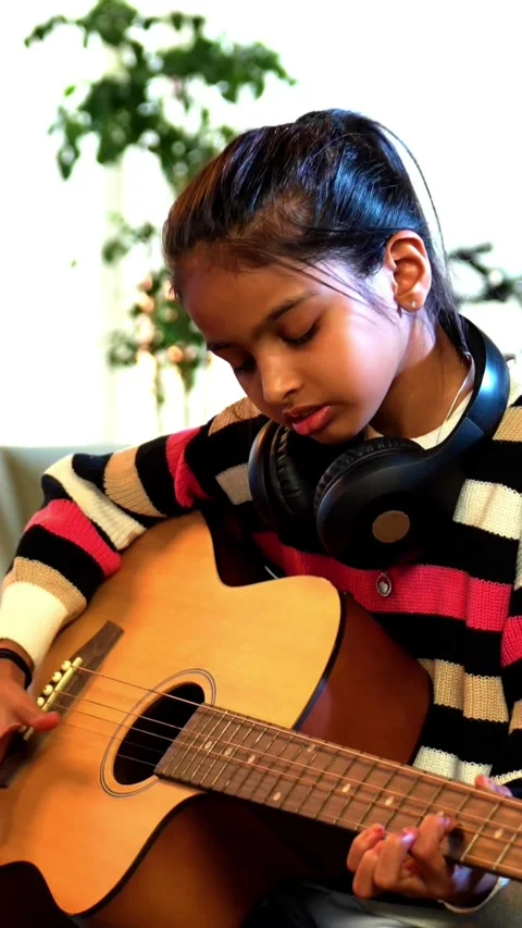 Young Indian kid practicing acoustic guitar at home online Stock Footage 343214320