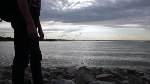 A young indian look man standing on the stone beach looking forward on the sea Stock Footage 66474751