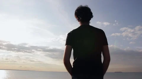 A young indian look man standing on the stone beach looking forward on the sea Stock Footage 66475291