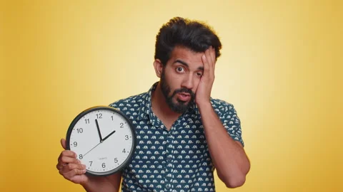 Young indian man with anxiety checking time on clock, running late to work Stock Footage 240779180