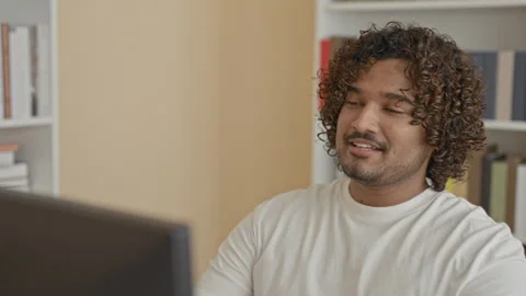 Young indian man at computer, hands behind head and leaning back smiling in.. Video stock 337402792