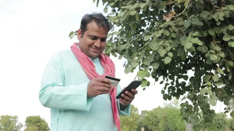 Young Indian man farmer using smartphone to make online payment with debit card Stock Footage 150373908