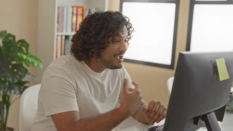 Young indian man with hands over mouth, seated at a desktop computer reacti.. Stock Footage 337402782