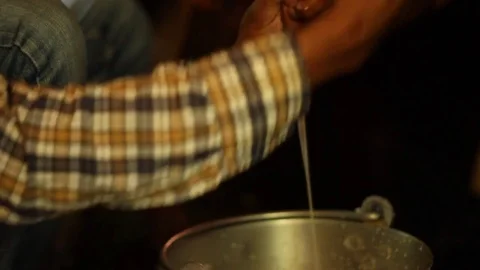 Young Indian man milks cow, close up, pan and tilt between man and teets Stock Footage