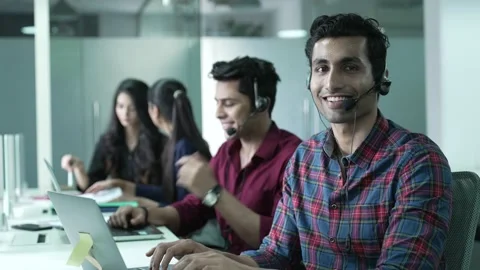 Young Indian man operator look at camera smile taking calls smile. Видео 170125804