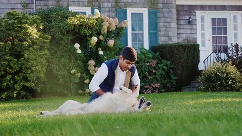 A young Indian man is playing with a dog in his backyard. Favorite pet Stock Footage 82109802