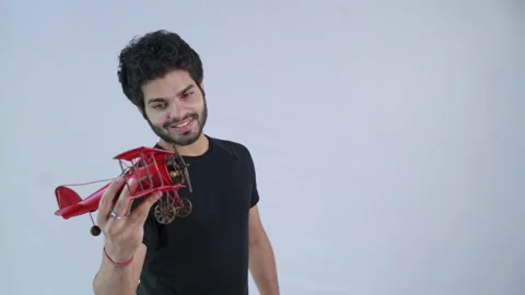 Young Indian man playing with a small airplane toy against white background. Stock Footage 170574882
