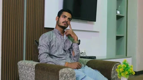 Young Indian man sitting on a sofa and lost in deep thought 動画素材 330390904