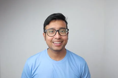 A young indian man in spectacles looking towards the camera and smiling with Stock Photos
