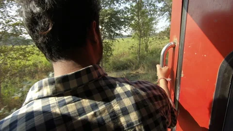 Young Indian man standing back to camera at door of moving train, India Stock Footage 167499061