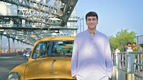 Young Indian man standing in front of an iconic with vintage yellow cab smiling. Video stock 266128144