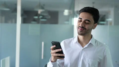 Young Indian man standing office room and chatting and texting on smart phone. Video stock 170176972