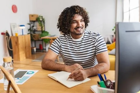Young Indian man studying with notebook at home desk Stock Photos