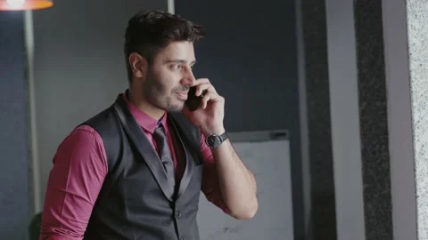 Young Indian man talking mobile phone with modern office building. Видео 169386612