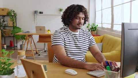 Young Indian man using computer in modern home office Stock Footage 345096592