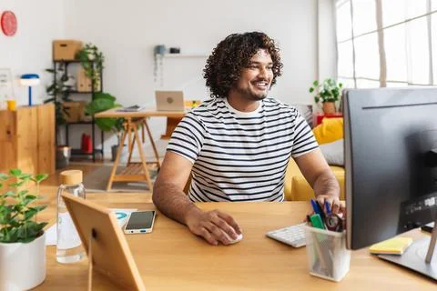 Young Indian man using computer in modern home office 스톡 사진
