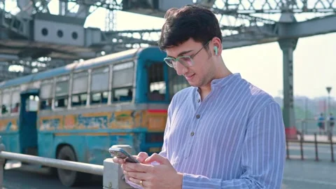 Young Indian man using a mobile phone to type a text message on a Howrah bridge. Vidéo 266128348
