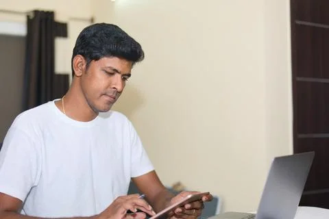 Young indian man using tablet and laptop computer at home Stock Photos