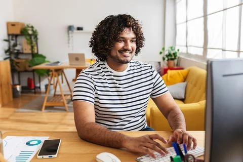 Young Indian man working on desktop computer at home office 스톡 사진