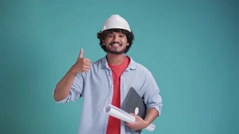Young Indian or arabic architect man with helmet and holding blueprints and Stock Footage 238771691