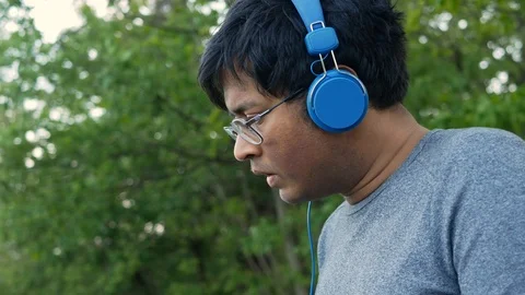 Young Indian student or freelancer working on a laptop sitting on a park bench Stock Footage 109048829