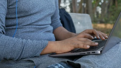 Young Indian student or freelancer working on laptop sitting on a park bench Stock Footage 109050247