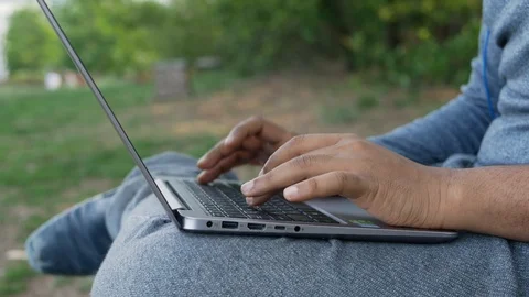 Young Indian student or a freelancer working on a laptop sitting on a park bench Stock Footage 109540717