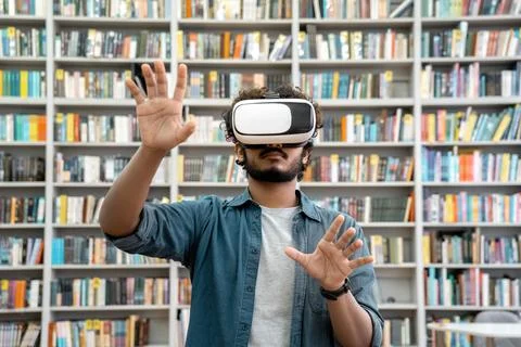 Young indian student using VR simulator for studying in university library Stock Photos