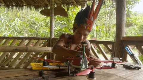 Young indigenous man is trying to fix a drone by connecting a electrical wire to Video stock 113179823