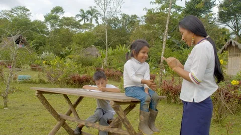 Young indigenous woman teaches basic math to a small girl while a boy behind Видео 113178862