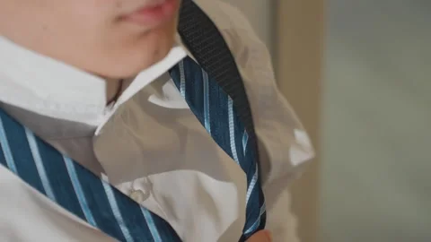 Young individual arranging necktie with focused morning ambiance. Man in white Stock Footage 342058081
