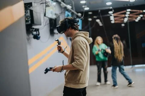 Young individuals exploring virtual reality experiences in an indoor gaming Stock Photos