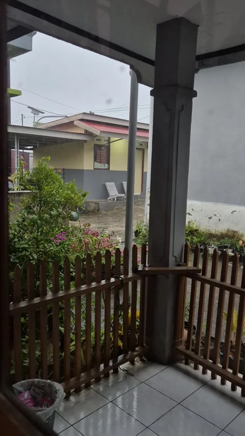 A young Indonesian schoolboy playing joyfully in the heavy rain Stock Footage 336401375