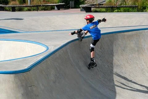 Young Inline Skater Performing Trick In Concrete Skatepark Stock Photos