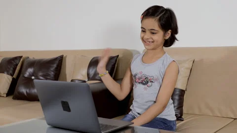 Young innocent kid busy doing a video call from her laptop - modern technology Vídeos de archivo 133875722