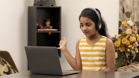 Young innocent kid busy doing a video call from her laptop - modern technology Stock Footage 135296490