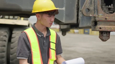 Young inspector checks a blueprint while performing quality control on heavy Stock Footage 338295070