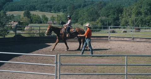 Young instructor teaching female student on horseback in riding pen Stock Footage 105000320