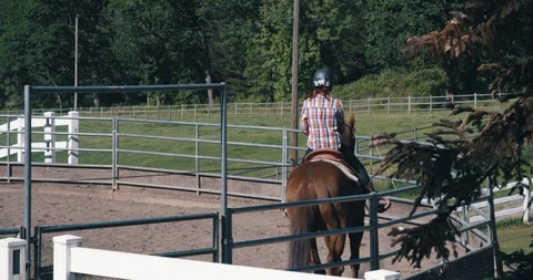 Young instructor teaching female student on horseback in riding pen Stock-Footage 105011766