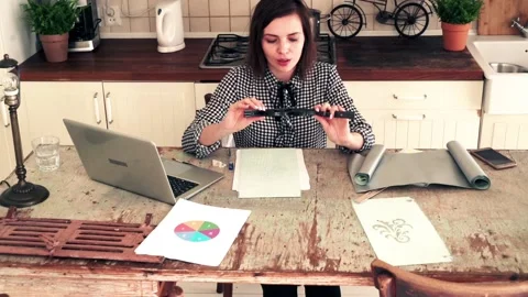 Young interior designer looking at ornament template by table in the kitchen Видео 102031418