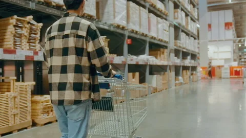 A young Interior designer man pushing supermarket cart looking for home decor 動画素材 190098467