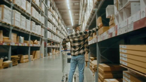 A young Interior designer man pushing supermarket cart looking for home decor Видео 190098667