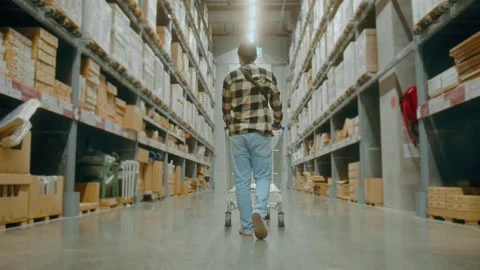 A young Interior designer man pushing supermarket cart looking for home decor Vídeo Stock 190099108