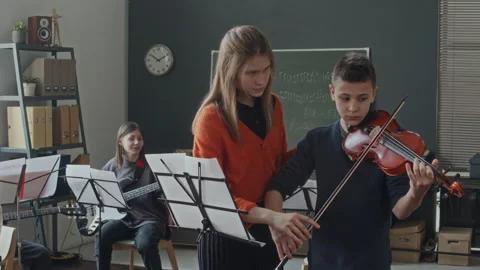 Young Intern Teaching Teen Boy to Play Violin in Music Class Stock Footage 280257325