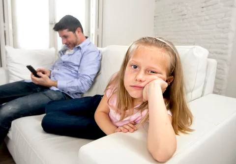 Young internet addict father using mobile phone ignoring his little sad daughter Stock Photos