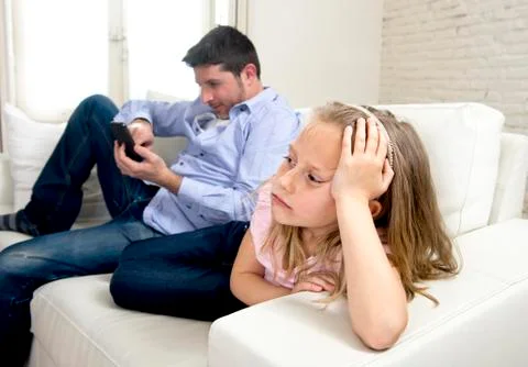 Young internet addict father using mobile phone ignoring his little sad daughter Stock-Fotos