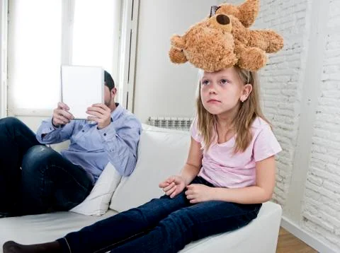 Young internet addict father using digital tablet  ignoring little sad daughter Stock Photos