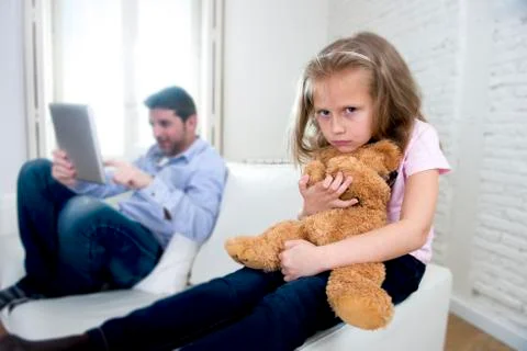 Young internet addict father using digital tablet  ignoring little sad daughter Stock Photos
